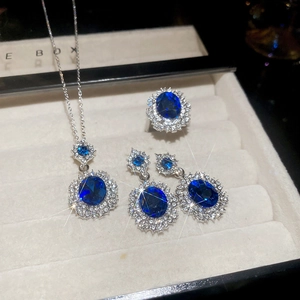 Macro shot of silver jewelry set with oval blue gemstones and halo diamonds in a box