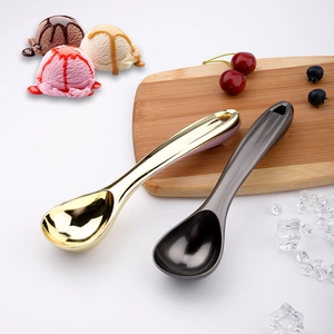 Polished metal ice cream scoops in gold and grey on a rustic wooden board with fruit