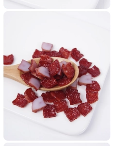Close-up of realistic PVC miniature smoked meat cubes on a wooden spoon and ceramic plate