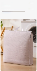 Close-up of white honeycomb mesh laundry bag with handle and side zipper detail