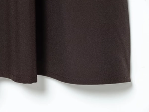Detailed macro shot of the deep brown midi dress hem showing premium woven fabric texture