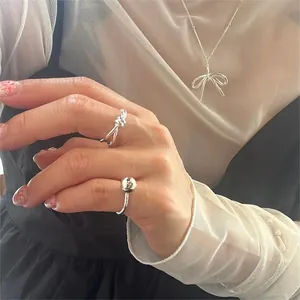 Detail of silver S925 minimalist bow necklace and matching knotted ring set on model