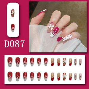 Detail of model wearing red and white press-on nails with bow and flame patterns, model D087