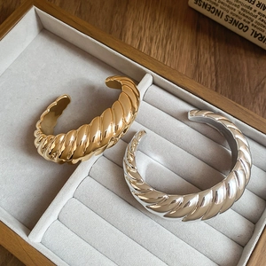Detail of twisted spiral cuff bracelets in polished gold and silver metal finishes