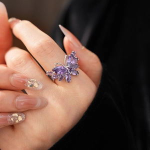 Gros plan d'une bague papillon en argent ornée de pierres de zircon violettes au doigt