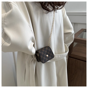 Close-up of brown monogram crossbody bag with a gold chain strap and snap closure