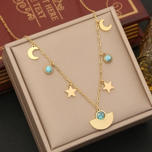Detail of gold star and moon necklace with turquoise charms on a jewelry box