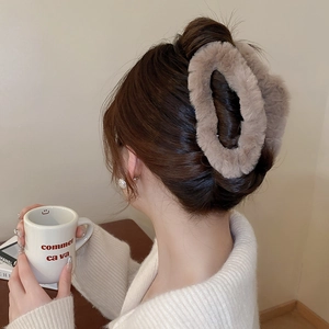Detail view of khaki plush hair claw clip used in an elegant bun hairstyle