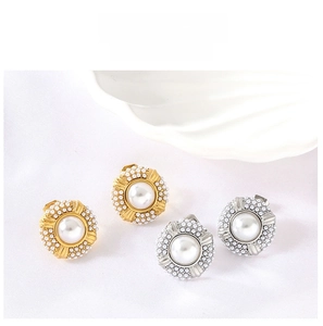 Detail of round 18K gold and silver plated earrings with pearls on white shell background