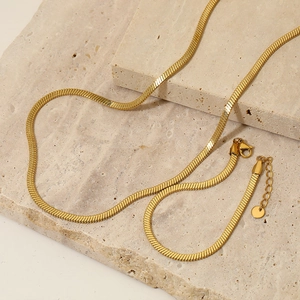 Gold PVD plated stainless steel flat snake chain necklace on stone texture blocks