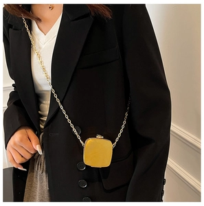 Close-up of a polished golden metallic mini square evening bag with sleek chain strap