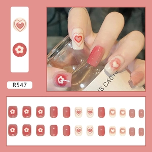 Detail van korte vierkante kunstnagels met roze blush verloop en bloem- en hartontwerpen