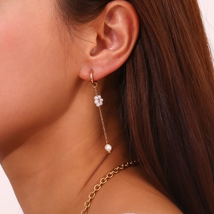 Detail of long tassel earring with mini pearl flower and gold chain on model