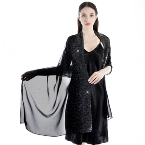 Detail of elegant black chiffon shawl with sparkling starry rhinestones on soft mesh fabric