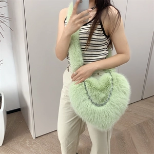 Close-up of light green heart-shaped plush crossbody bag with silver metal chain detail