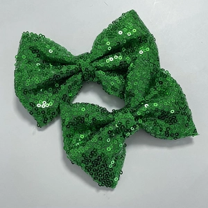 Close-up of two green sequin bow appliques for DIY hair clips and clothing decor