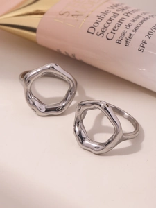 Macro view of geometric silver rings with irregular hollow waves and glossy finish