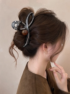 Detail of gunmetal hair claw with brown amber bead on model's sleek updo hairstyle