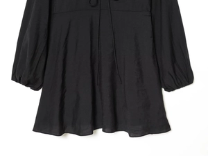 Detailed close-up of a black long-sleeve dress with lantern sleeves and hemline texture
