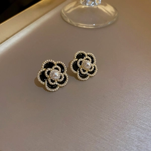 Macro detail of French vintage black camellia stud earrings with gold plating and pearls