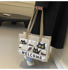 Detail of beige canvas tote bag with cat comic print and brown leather handles