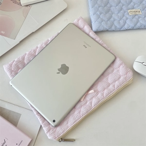 Detail of pink plaid laptop sleeve with quilted heart texture and a small bow decoration