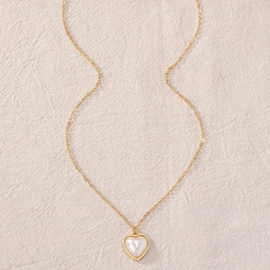 Detailed view of heart pendant necklace with gold chain and white pearl inlay