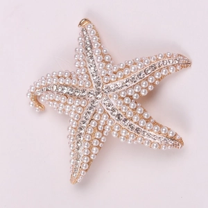 Close-up of golden starfish brooch with pavé set white pearls and sparkling rhinestones
