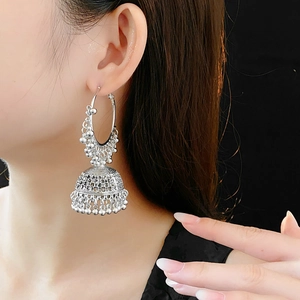 Detailed view of vintage silver ethnic Jhumka earrings with ornate bells worn by model