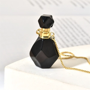 Macro view of geometric black gemstone perfume bottle pendant with gold metal chain