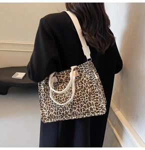 Detail of leopard print canvas tote bag featuring wide shoulder strap and outer pocket