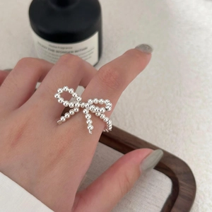 Detailed macro shot of a beaded silver bow ring worn on a finger in a lifestyle setting