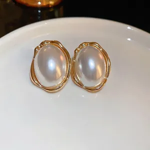 Boucles d'oreilles perles ovales vintage avec bordure dorée sur plateau blanc