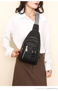 Close-up of black PU leather chest bag with patterned wide strap and pebble texture