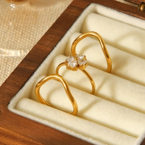 Macro shot of three-piece gold ring set with zirconia four-leaf clover on beige velvet