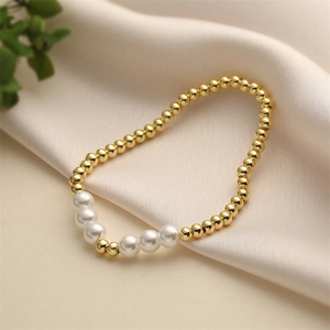 Elegant beaded bracelet with golden copper beads and pearls on silk background