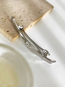 Close-up of polished silver wavy spring hair clip with minimalist metallic texture