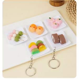 Dettaglio di portachiavi assortiti in resina a forma di cibo in miniatura su vassoio bianco