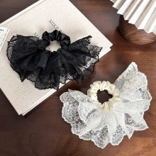 Close-up of black and cream satin scrunchies with elegant lace trim on a wood surface