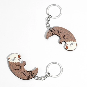 Detail of interlocking wooden otter keychains showing wood grain and heart patterns