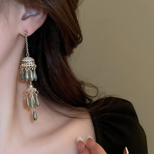 Detail of elegant gold tassel earrings featuring olive green teardrop beads and pearls