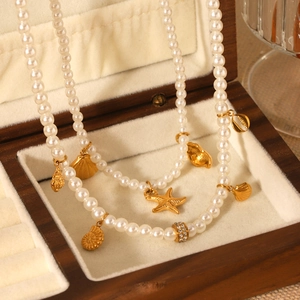 Double-layered necklace featuring gold shells, starfish charms, and white pearls in a box