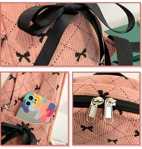 Detail of pink corduroy school backpack featuring bow ribbon and metal zipper texture
