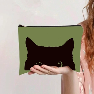 Vue portée d'une trousse à maquillage en toile verte avec silhouette de chat noir