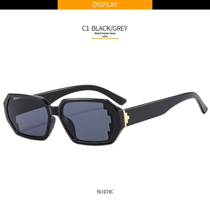 Detail view of black geometric sunglasses with golden metal hinges and dark grey lenses