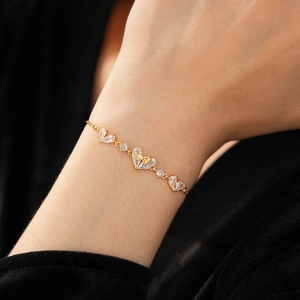 Detail of 18K gold plated heart bracelet with zircon bow on model's wrist