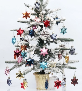 Close-up of shiny multicolored star ornaments hanging on a snowy Christmas tree branch