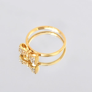 Elegant gold bow ring with sparkling zircons and mirror reflection on grey background