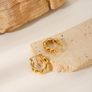 Detailed view of 18K gold plated stainless steel twisted hoop earrings on stone display