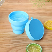 Detailed top view of a blue collapsible silicone cup on a light wooden table background